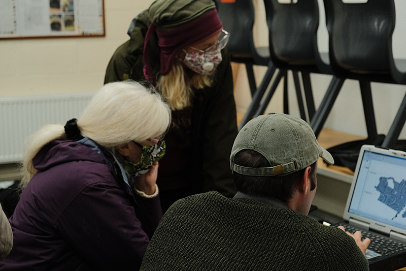 three people looking at a computer