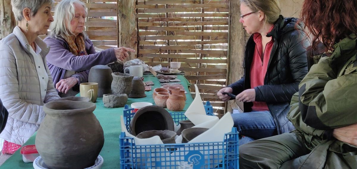 four people sitting at table with pots