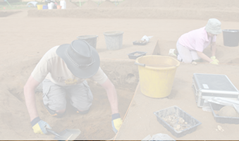 two people excavating in sandy field