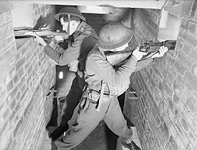 staged wartime photo of two armed men at windows in narrow gunhouse